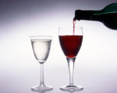 Pouring red wine into a glass, with another glass of white wine.